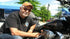 Man crouching and pointing at custom motorcycle cover