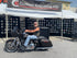 man with leather vest sitting on a custom black motorcycle in front of the custom engraving event tent